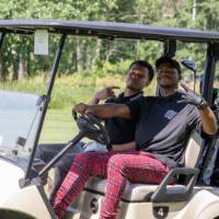 Two alumni riding in golf cart